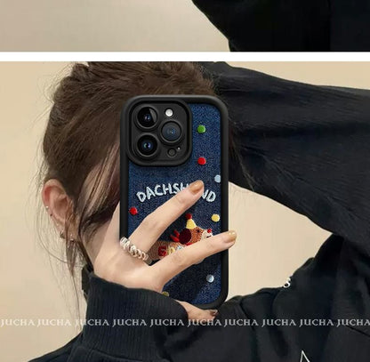 A luxurious smartphone case made of denim material with embroidered dogs. Compatible with iPhones.